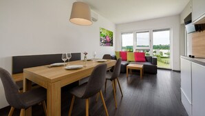 A modern dining area with a wooden table, grey upholstered chairs, and a hanging light fixture. - Classy Holiday Home in Lutzmannsburg (Zsira)
