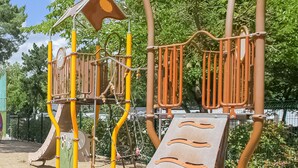A playground with a slide, climbing structures, and a small shelter.