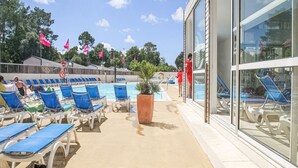 A poolside area with lounge chairs, a large planter, and a building with large windows.