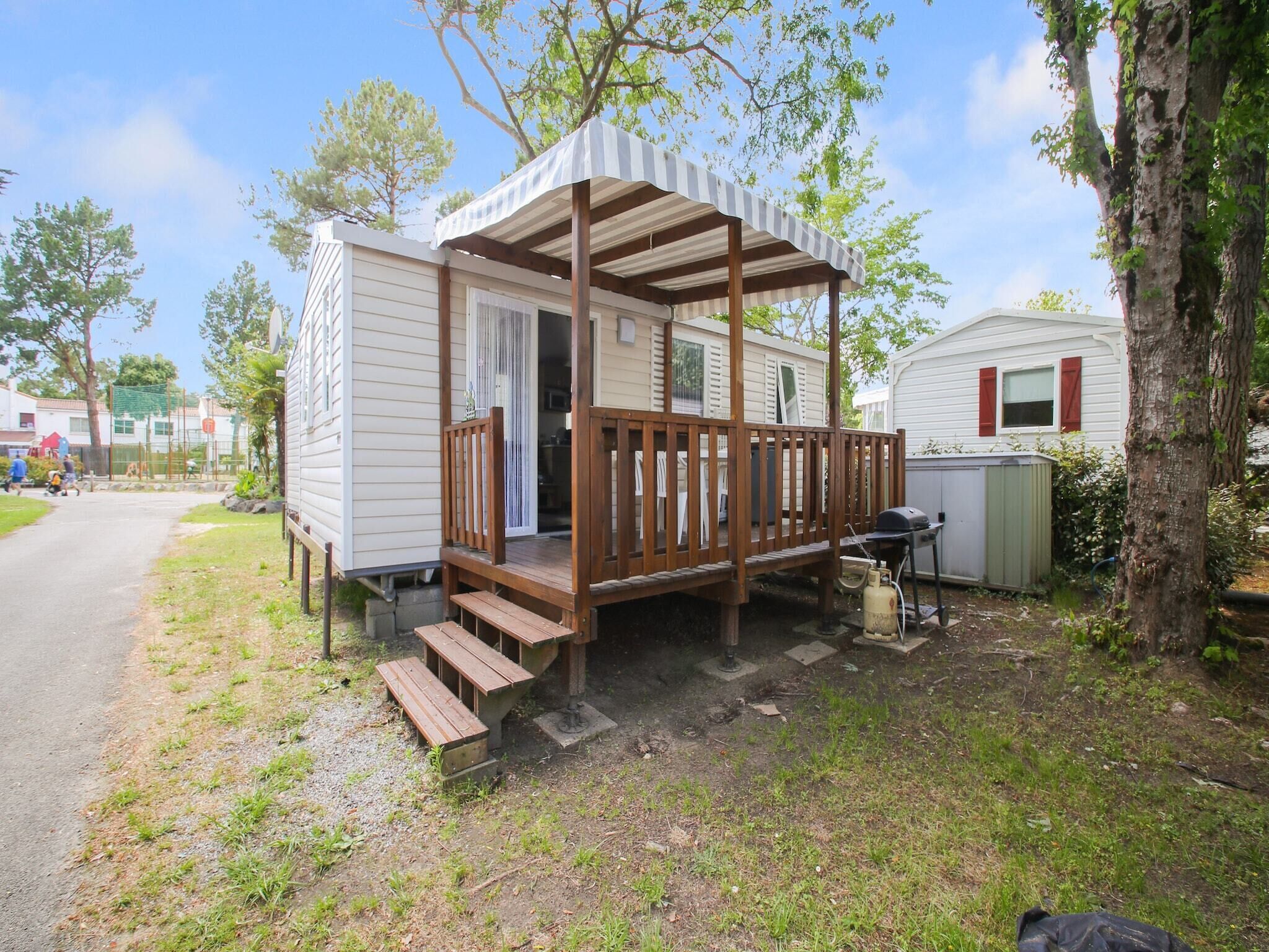 A mobile home with a wooden porch and a covered outdoor area.
