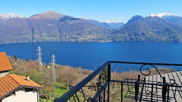 Un paisaje de montaña con un lago y una casa de techo rojo.