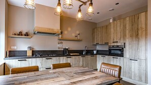 A modern kitchen with a large wooden dining table, built-in cabinets, and a gas stove. - Farmhouse Nijverdal near Sallandse Heuvelrug (Nijverdal)