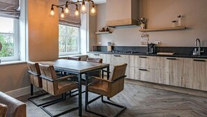 A modern kitchen with wooden cabinets, a dining table with chairs, and a hanging light fixture. - Farmhouse Nijverdal near Sallandse Heuvelrug (Nijverdal)