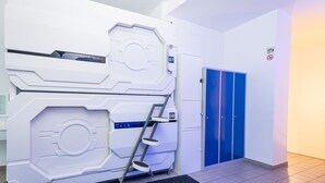 Una habitación moderna y blanca con una máquina grande de aspecto futurista, una escalera y dos taquillas azules.