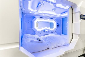 A futuristic room with a bed, a control panel, and a window. - Space Homes Hostel - Inner City (Vienna)