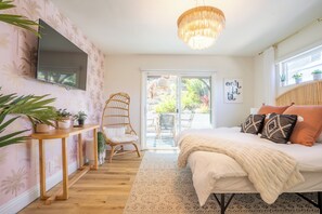 Une chambre à coucher avec un lit, une télévision, une table en bois, une chaise et une vue sur l’extérieur.