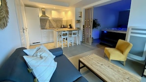 A modern living room with a sofa, a coffee table, and a yellow armchair. - Gîte with private Jacuzzi (St martin choquel)