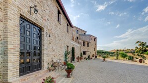 A stone building with a large black door, outdoor seating, and potted plants.