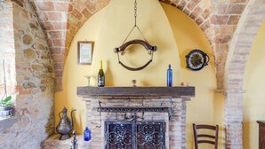 A rustic room with a brick fireplace, a hanging light fixture, and a wooden chair.