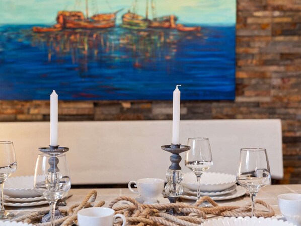A dining table set with white plates, wine glasses, and candles, with a painting of a harbor in the background. - Holiday Home in Vrana near Lake and Beach (Vrana)