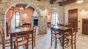 A rustic dining area with stone arches, wooden tables, and chairs. - Holiday Home in Urbania with Hill Views (Urbania)
