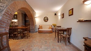 A dining area with brick arches, wooden furniture, and a central sofa. - Mansion in Prodo near Lake Bolsena (Prodo)