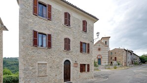 A stone building with multiple windows and a central door, surrounded by a street and other buildings. - Mansion in Prodo near Lake Bolsena (Prodo)