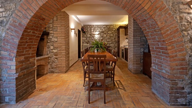 A dining area with a brick archway, stone walls, and a wooden table with chairs. - Mansion in Prodo near Lake Bolsena (Prodo)
