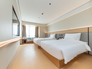 Una habitación de hotel con dos camas, un ventanal grande, una mesita de noche y un espejo.