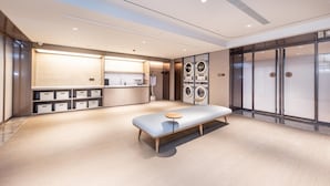 Une chambre d’hôtel moderne avec un grand lit, une petite table, un lave-linge intégré et une armoire.