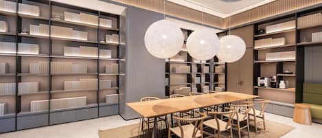 A modern interior with a long dining table, multiple chairs, and a large bookshelf filled with books.
