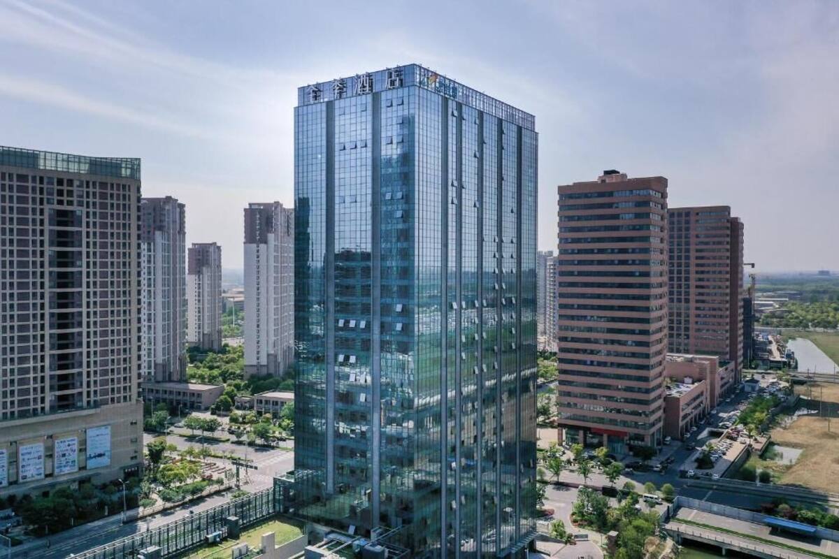 A high-rise building with a glass facade, surrounded by other buildings and a clear sky.
