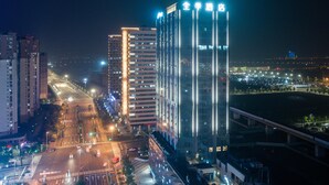Une vue nocturne d’une ville, avec des bâtiments illuminés, une autoroute et un pont.