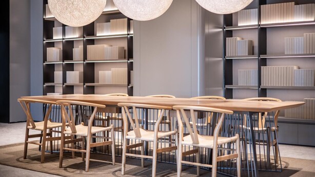Un espace repas moderne avec une longue table en bois et des chaises, entouré d’étagères.