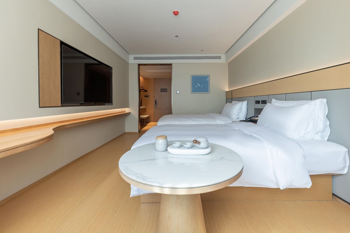 A hotel room with a bed, bedside table, and a television.