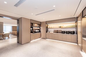 Una cocina moderna con electrodomésticos integrados, un comedor con mesas y vistas a un paisaje verde.