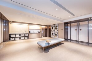 Habitación de hotel moderna con una cama grande, una mesita pequeña, lavadora incorporada y armario.