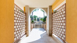 A corridor with a tiled floor, a staircase leading to an outdoor area, and a wooden fence with a grid pattern on both sides.