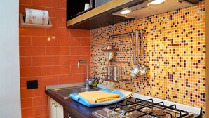 A kitchen with a gas stove, sink, and a backsplash with colorful tiles.