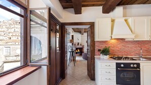 Une cuisine avec un mur en briques, une cuisinière à gaz et des armoires blanches.