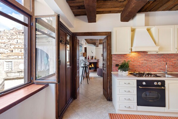 A kitchen with a brick wall, a gas stove, and white cabinets.