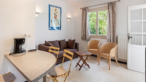 A cozy living room with a round table, two chairs, a sofa, and a coffee machine. - Flat in a beautiful building with pool (Mèze)