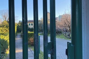 Ein gepflasterter Weg führt zu einem Gebäude mit einem grünen Metalltor.