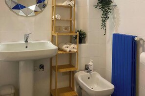 Une salle de bain équipée d’un lavabo, d’un bidet, d’un porte-serviettes et d’un miroir.