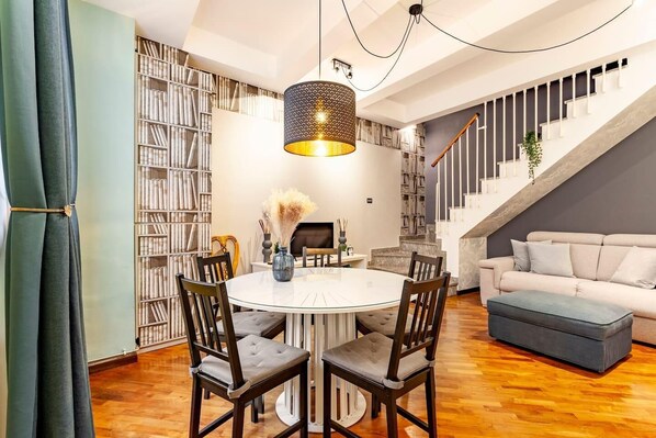 Un vaste espace de vie comprenant une table à manger ronde, plusieurs chaises, un canapé, un escalier et une bibliothèque.