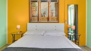 Ein Hotelzimmer mit einem großen Bett, zwei Nachttischen, einem Bild über dem Bett und einem Spiegel an der Wand.