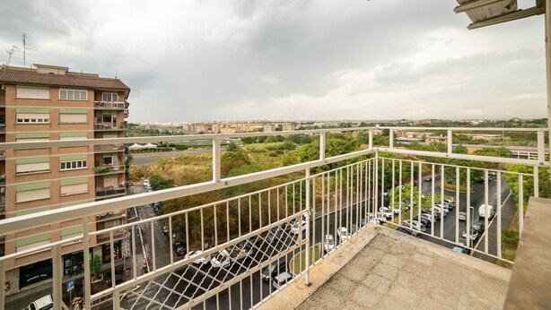 Ein Hochhaus mit einem Balkon, der auf einen Parkplatz und die Stadt Aussicht bietet.
