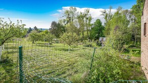 A fenced garden with trees and a brick building. - Cottage in Aywaille with Garden (Aywaille)