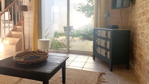 A room with a staircase, a sliding glass door leading to an outdoor area, a television mounted on the wall, and a wooden cabinet. - ELOISE             . (Sainte-Marie-de-Ré)