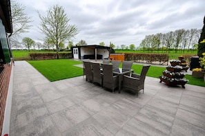 A patio with a dining table and chairs, a small building, and a well-maintained lawn. - Farmhouse in Silvolde with Hot Tub (Silvolde)