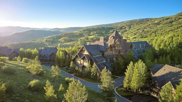 A large lodge with multiple buildings, surrounded by lush greenery and hills. - Bachelor Gulch Village (Avon)