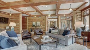 A log cabin interior with a cozy living area featuring sofas, a coffee table, and a fireplace. - Bachelor Gulch Village (Avon)