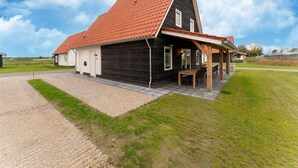 En toetages bygning med rødlægte tag, en overdækket veranda og en grusvej.