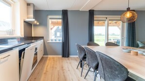 Et moderne køkken med træbordplade, indbyggede apparater og et spiseområde med bord og stole.
