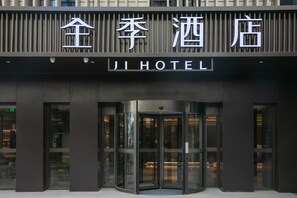 A hotel entrance with a revolving door and a sign above reading 'JI HOTEL'.