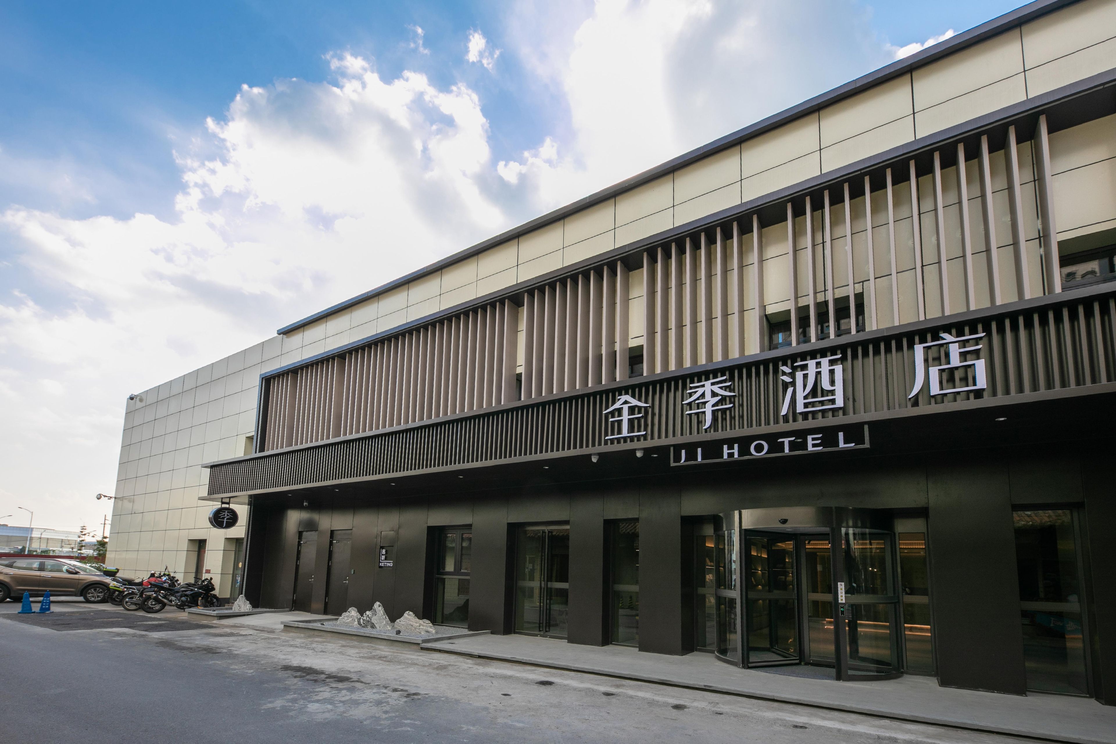A hotel with a modern facade, featuring a prominent sign with Chinese characters and the word 'HOTEL' in English.