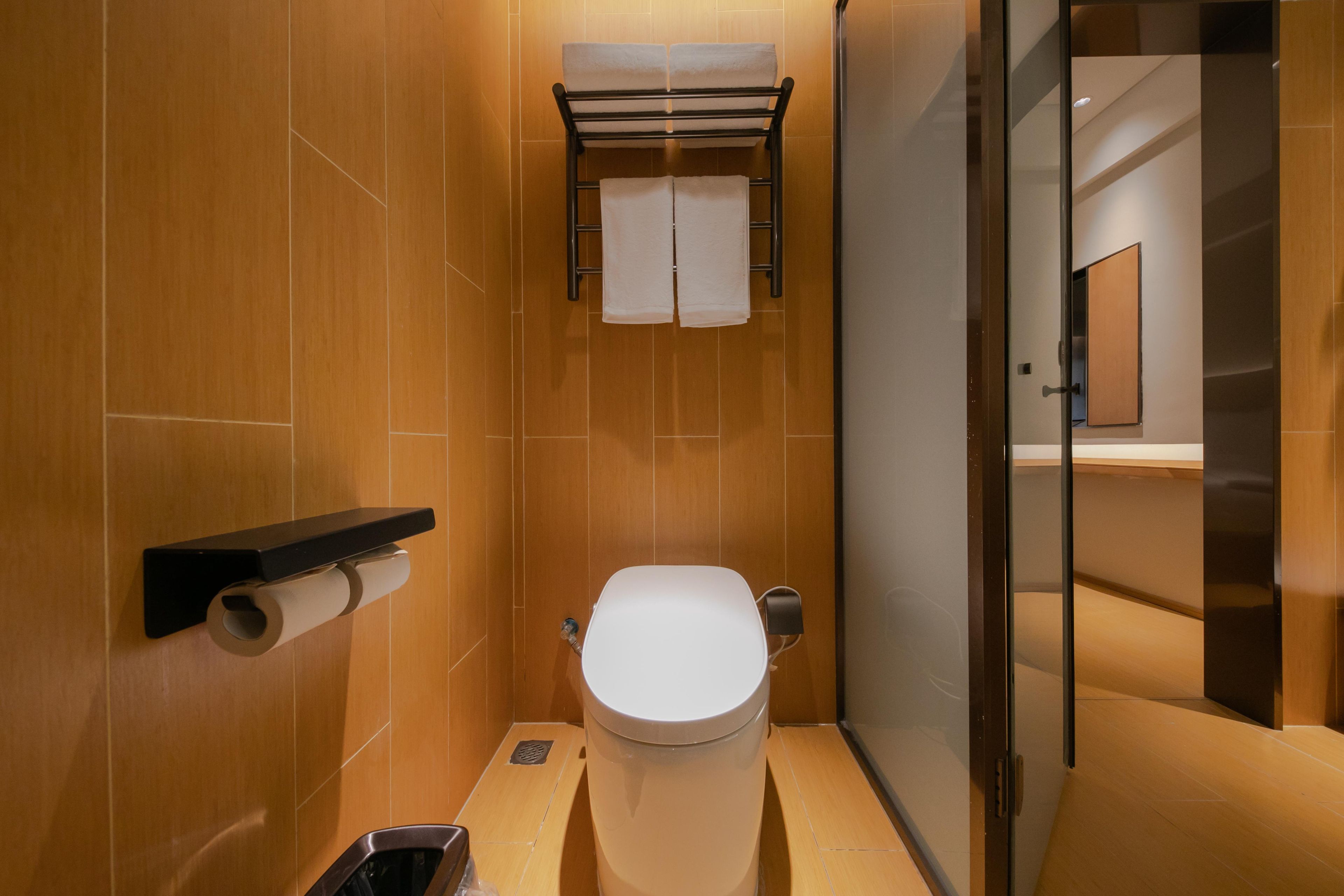 A modern bathroom with a toilet, a towel rack, and a toilet paper holder.