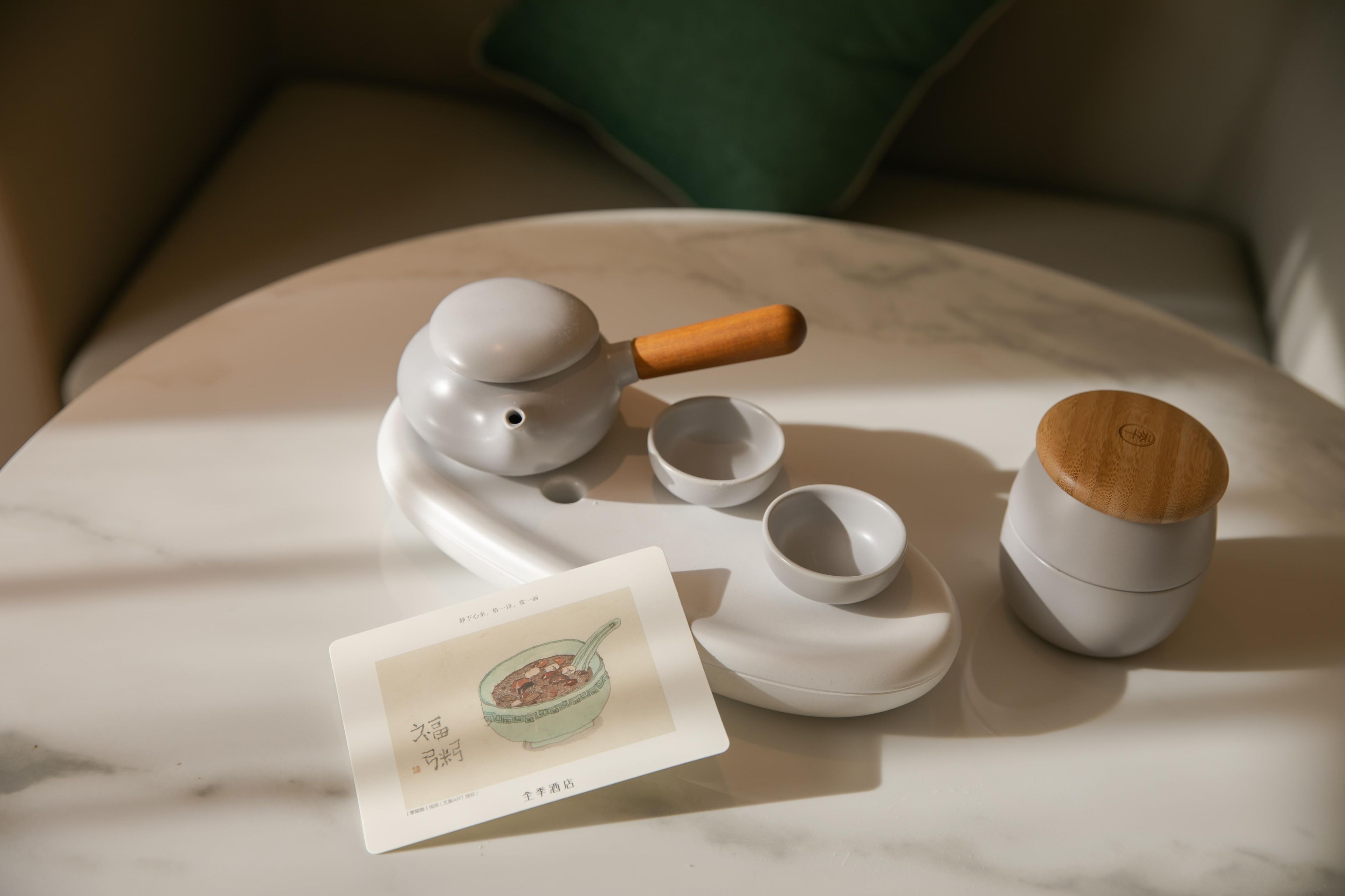 A tea set with a teapot, cups, and a wooden lid on a marble surface.