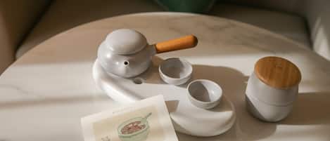 Un juego de té con tetera, tazas y una tapa de madera sobre una superficie de mármol.