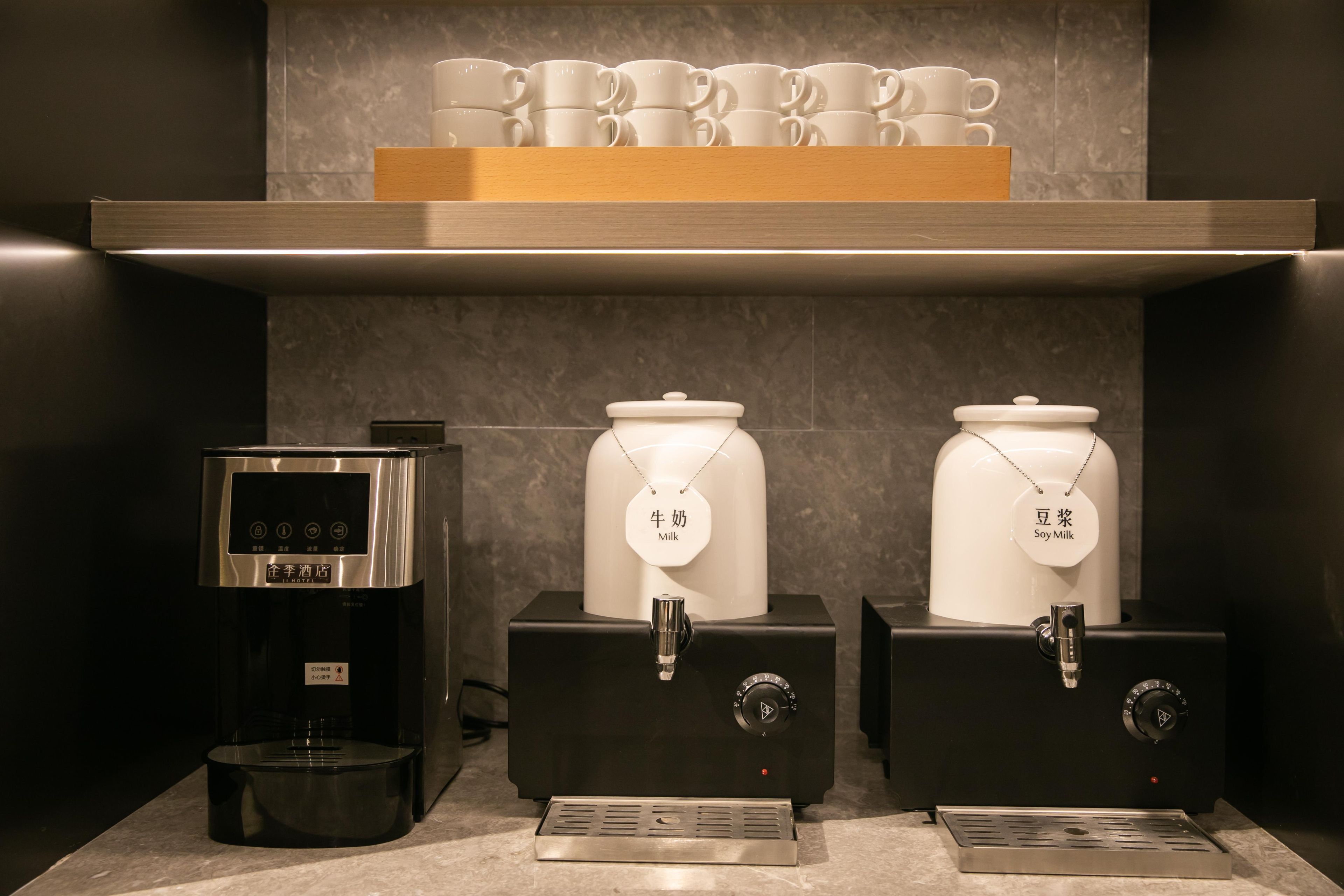 Une machine à café et deux distributeurs de lait, le tout installé dans un hôtel.